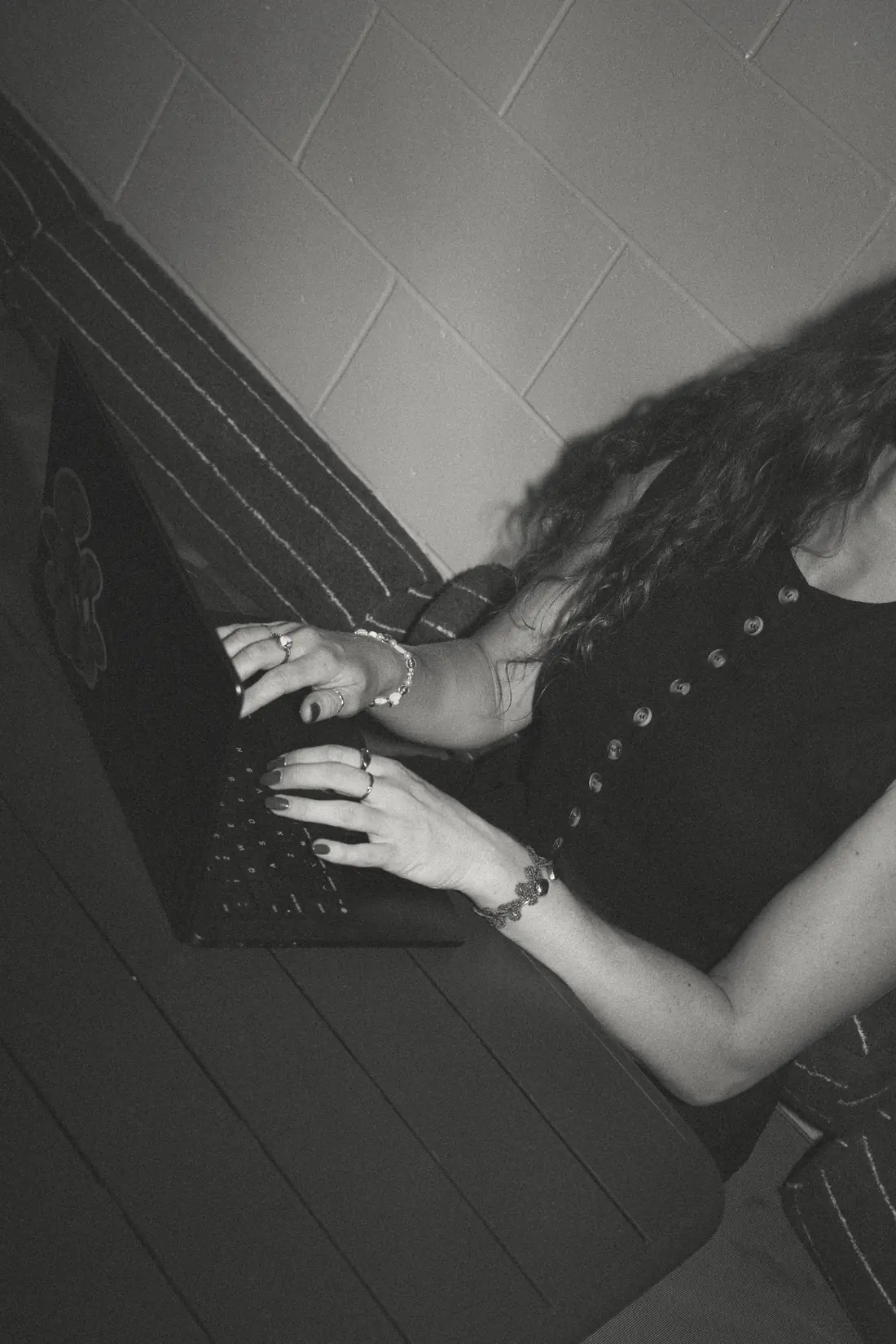 Black and white close-up of hands typing on a laptop