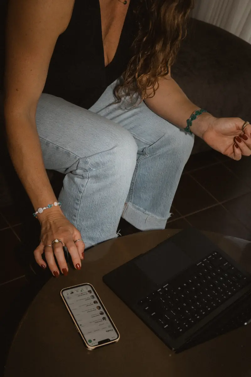 Amy with her phone and laptop, planning social media content